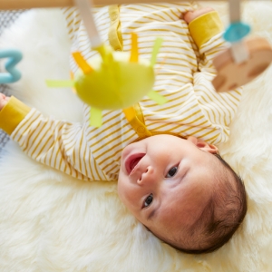 A baby lying on its back, playing with a dangling toy from Panda Crate