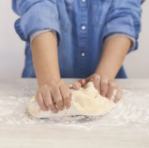 A young chef kneading dough and learning with tips from a Yummy Crate cooking science box